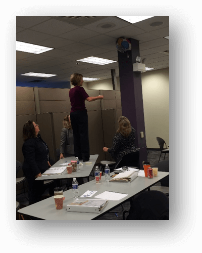 A woman standing on a desk participating in experiential learning.